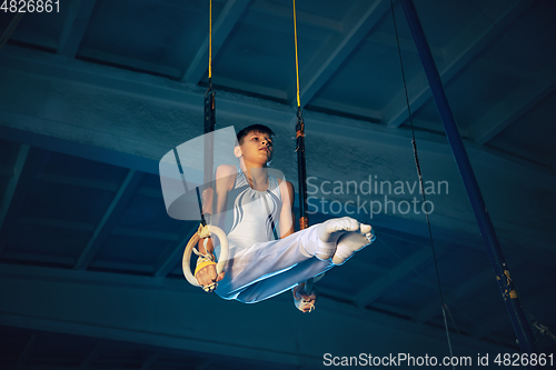 Image of Little male gymnast training in gym, flexible and active