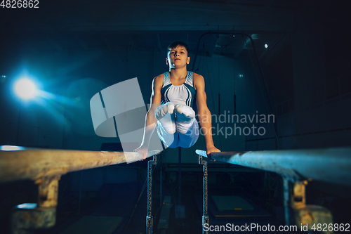 Image of Little male gymnast training in gym, flexible and active