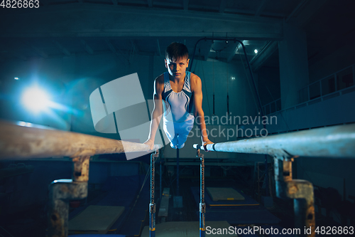 Image of Little male gymnast training in gym, flexible and active