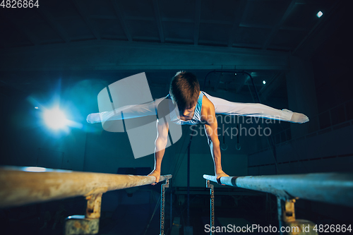 Image of Little male gymnast training in gym, flexible and active