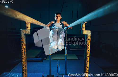 Image of Little male gymnast training in gym, flexible and active