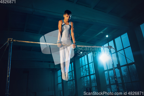 Image of Little male gymnast training in gym, flexible and active