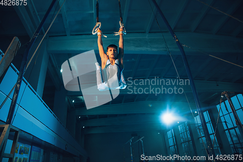 Image of Little male gymnast training in gym, flexible and active