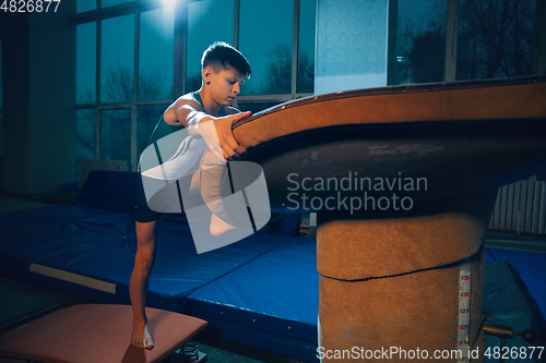 Image of Little male gymnast training in gym, flexible and active