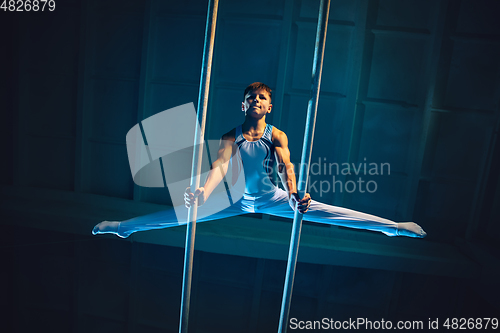 Image of Little male gymnast training in gym, flexible and active