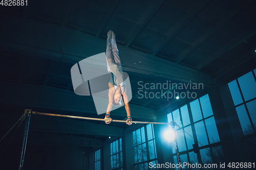 Image of Little male gymnast training in gym, flexible and active