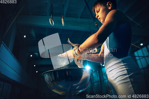 Image of Little male gymnast training in gym, flexible and active