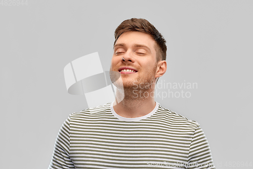 Image of smiling young man in striped t-shirt breathing