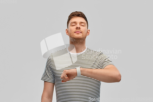 Image of calm young man with smart watch meditating