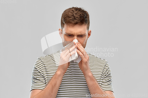 Image of young man with paper tissue blowing his nose