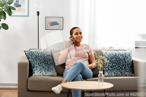 Image of african woman calling on smartphone at home