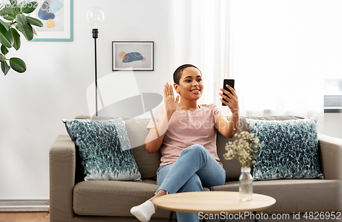 Image of woman with smartphone having video call at home