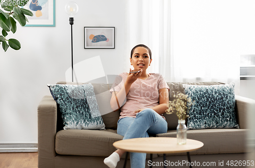 Image of woman recording voice with smartphone at home