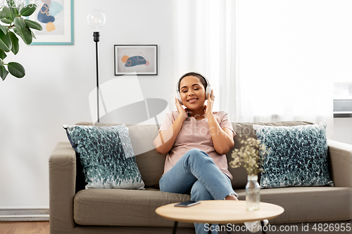 Image of woman with headphones listening to music at home