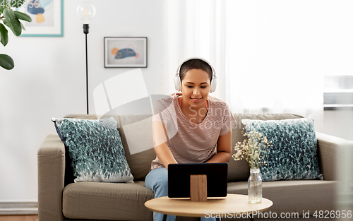 Image of woman with headphones and tablet computer at home