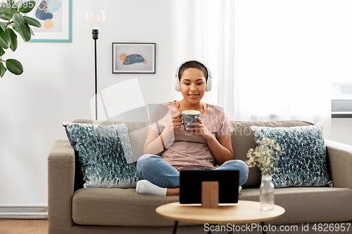 Image of woman with headphones and tablet pc drinking tea