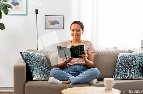 Image of african american woman reading book at home