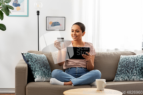 Image of happy woman with tablet pc and credit card at home