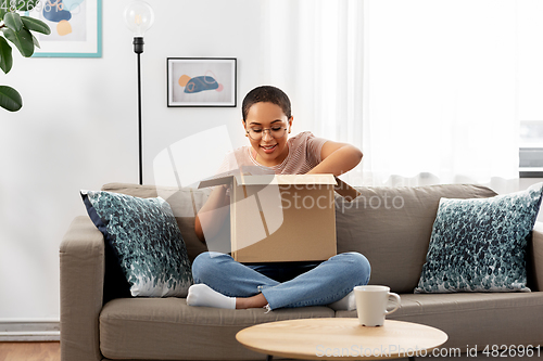 Image of african american woman opening parcel box at home