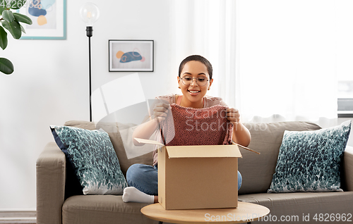Image of african american woman opening parcel box at home