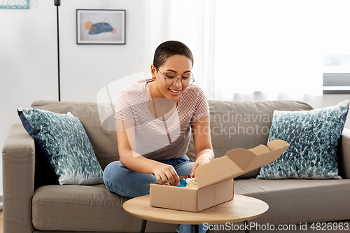 Image of african american woman opening parcel box at home