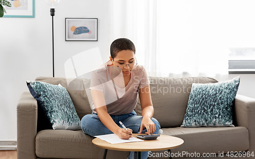 Image of african woman with papers and calculator at home