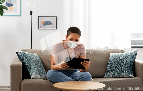 Image of woman in medical mask with tablet pc at home
