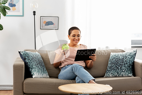 Image of african woman with tablet pc and apple at home