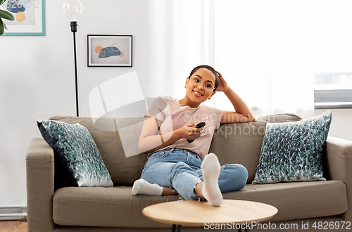 Image of happy african american woman watching tv at home