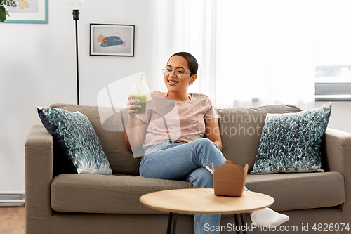 Image of african american woman drinking smoothie at home