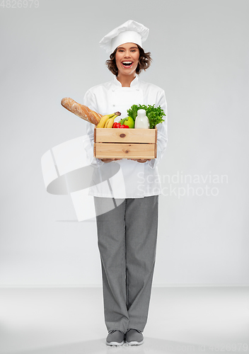 Image of happy smiling female chef with food in wooden box