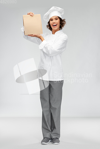Image of happy female chef with takeaway food in paper bag