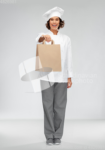 Image of happy female chef with takeaway food in paper bag