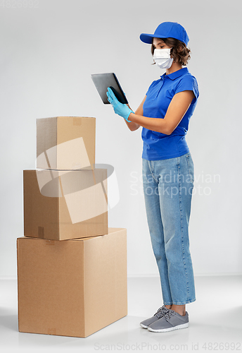 Image of delivery woman in mask with boxes and tablet pc