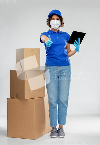 Image of delivery woman in mask with boxes and tablet pc