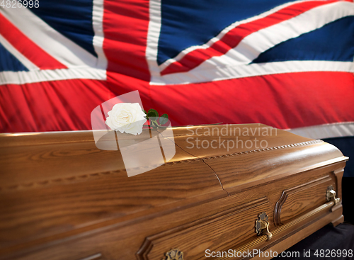 Image of rose flower on wooden coffin over flag of england