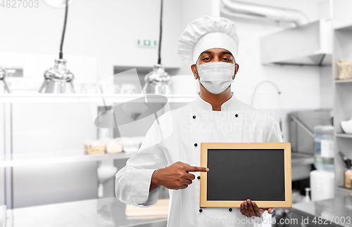 Image of chef in face mask with chalkboard at kitchen