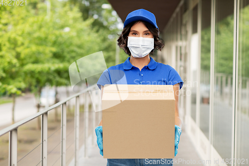 Image of delivery woman in mask holding parcel box outdoors