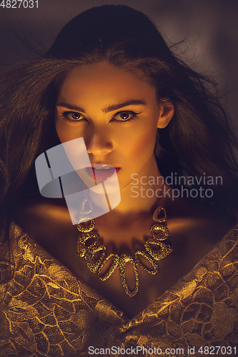 Image of beautiful young woman with necklace in golden light