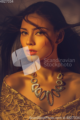 Image of beautiful young woman with necklace in golden light