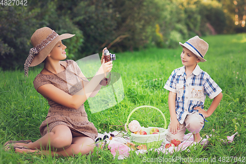Image of Little boy and teen age girl having picnic outdoors