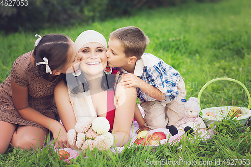 Image of mother with kids having picnic outdoors