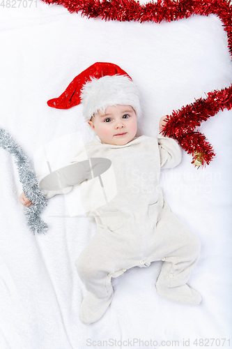 Image of beautiful baby boy in christmas hat lying