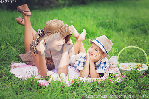 Image of Little boy and teen age girl having picnic outdoors