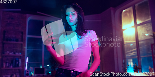 Image of Cinematic portrait of handsome young woman in neon lighted interior