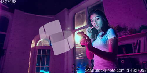 Image of Cinematic portrait of handsome young woman in neon lighted interior