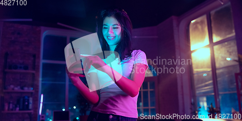 Image of Cinematic portrait of handsome young woman in neon lighted interior