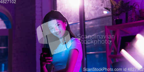 Image of Cinematic portrait of handsome young woman in neon lighted interior