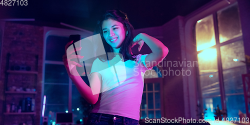 Image of Cinematic portrait of handsome young woman in neon lighted interior