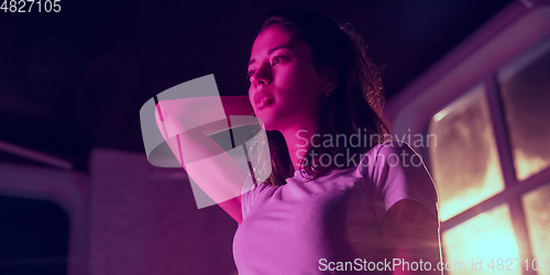 Image of Cinematic portrait of handsome young woman in neon lighted interior